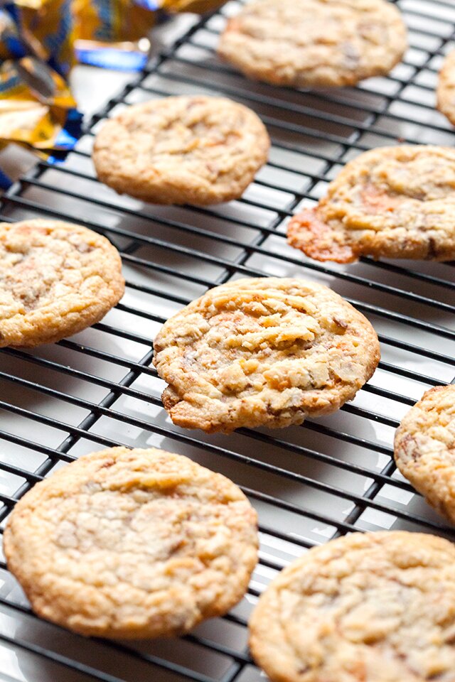 These chewy cookies are full of Butterfingers and stuffed with peanut butter buttercream; it's basically salty-sweet perfection | www.spachethespatula.com #recipe